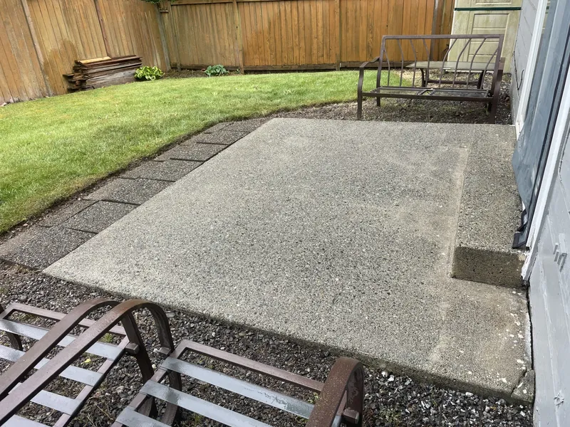 The same patio after pressure washing, concrete restored to a clean, even gray
