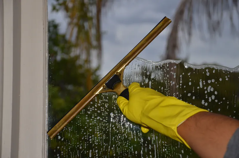 A squeegee clearing soapy water from a window pane